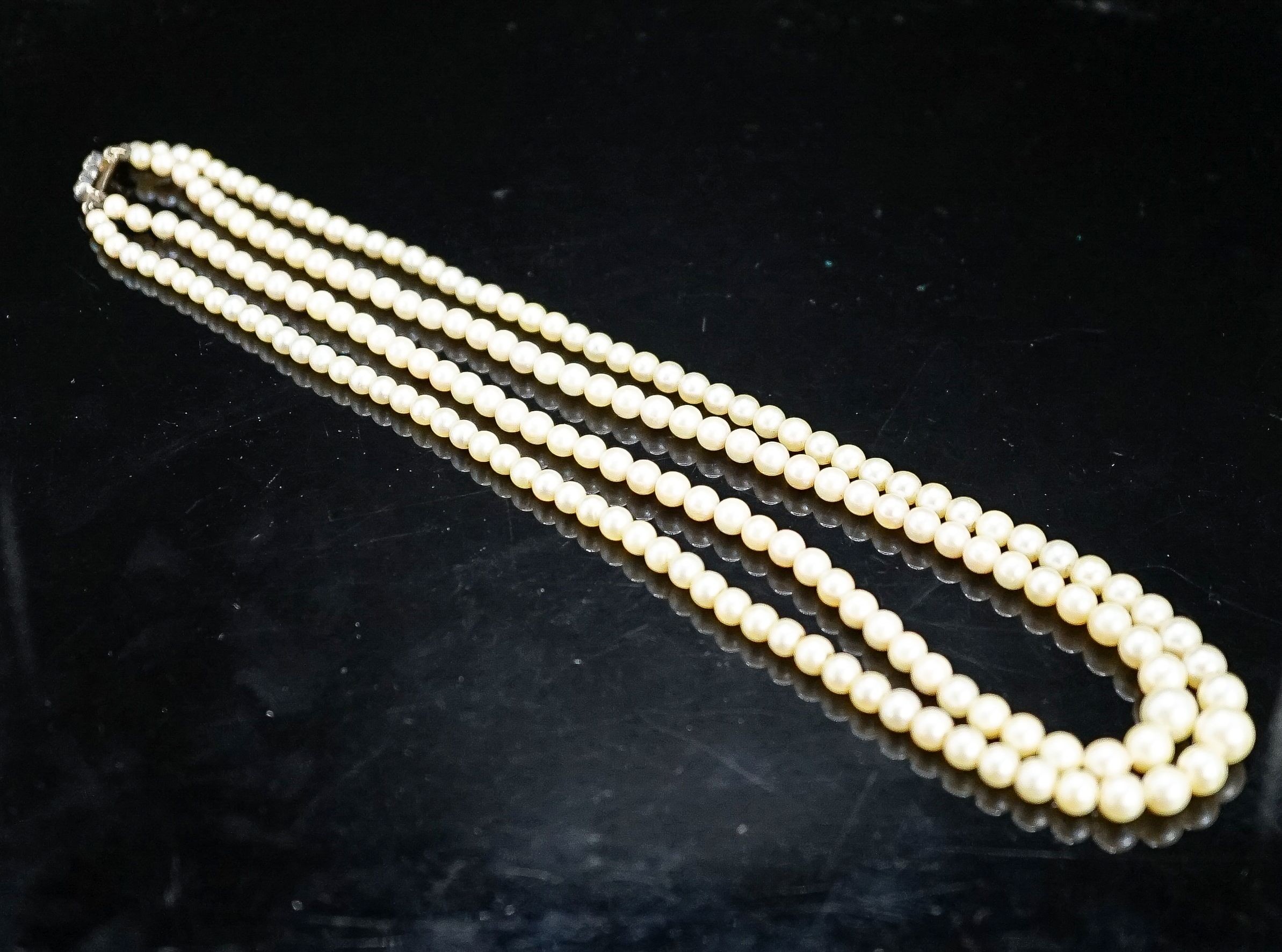 A double strand graduated cultured pearl choker necklace, with three stone diamond set clasp, 39cm.